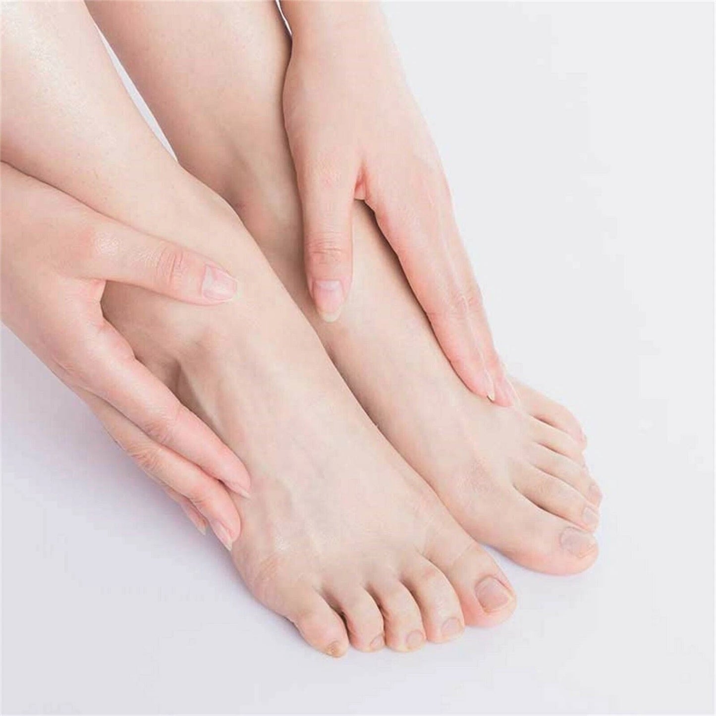 Close-up of a person's feet with hands gently holding them on a light background